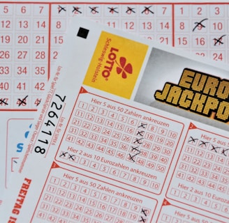 Three lottery tickets are displayed, including Eurojackpot and Super 6. Various numbers are marked on the tickets, with some crossed out and others checked. The Eurojackpot ticket is partially visible with the logo prominently displayed, and a ticket number is visible on one of the tickets.